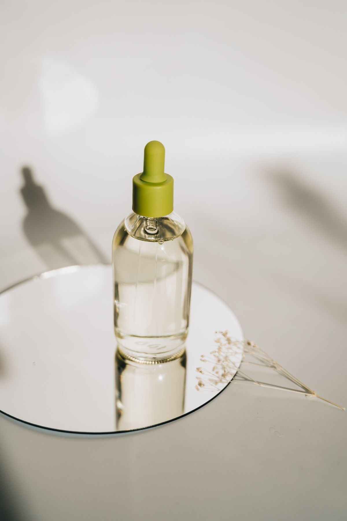 Unbranded glass dropper bottle on a mirror in natural light