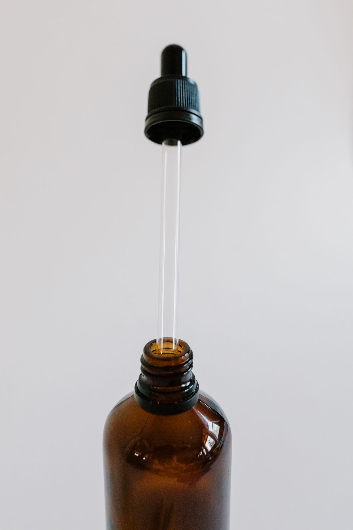 Glass pipette above an unbranded amber bottle